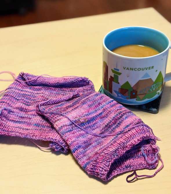A knitting project in front of a full mug of coffee.
